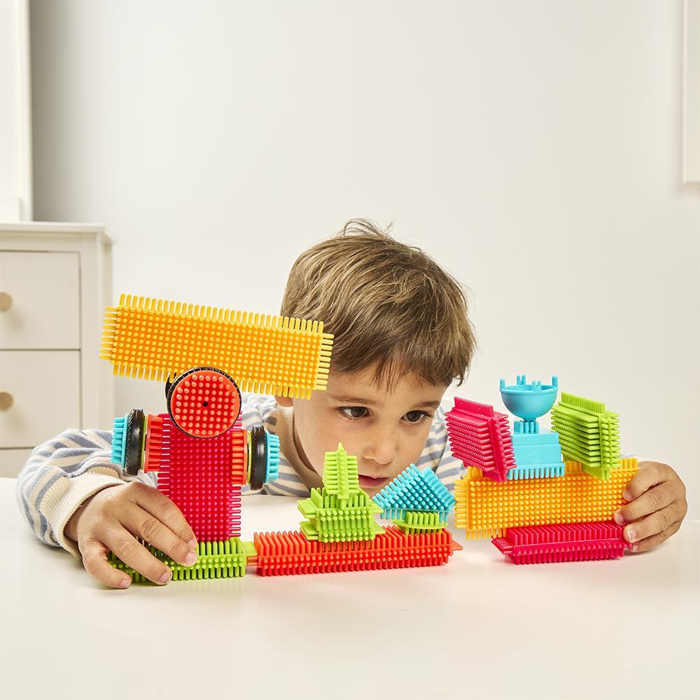 Deti hrajúce sa so stavebnicami Miniland Pegy Bricks na koberci